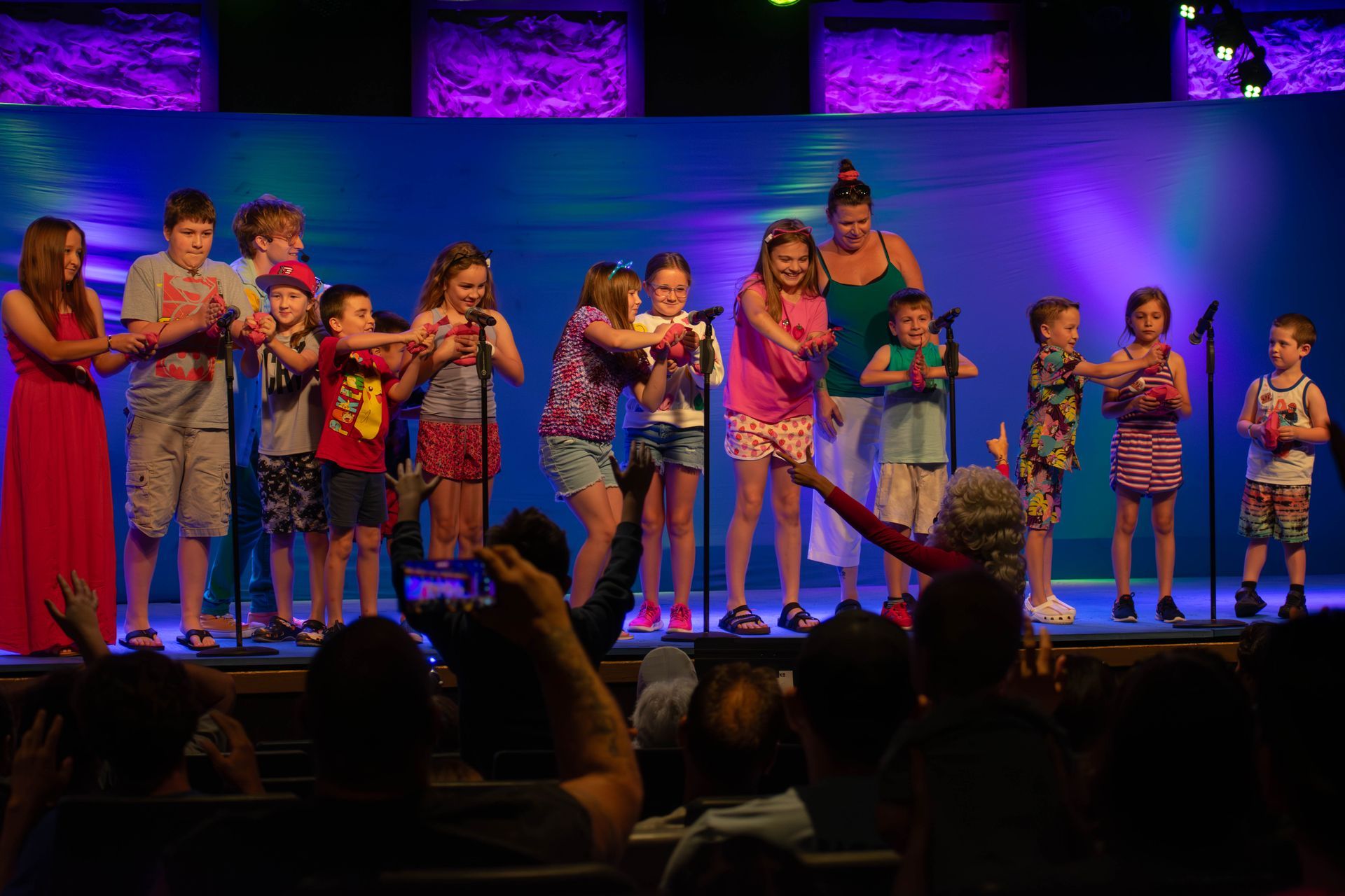 A group of children are singing into microphones on a stage.