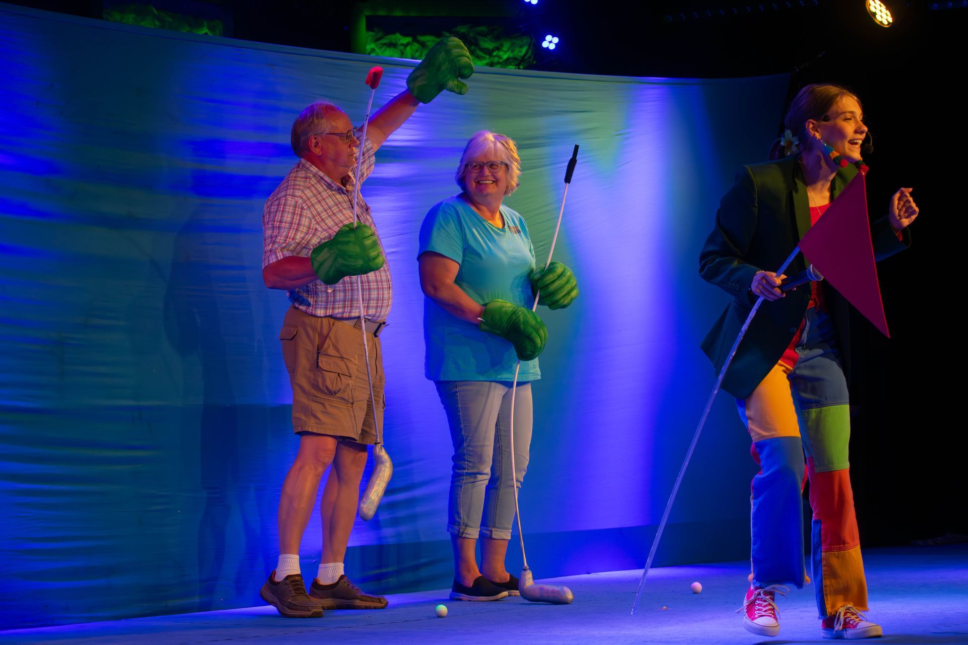 A group of people are standing on a stage holding golf clubs.