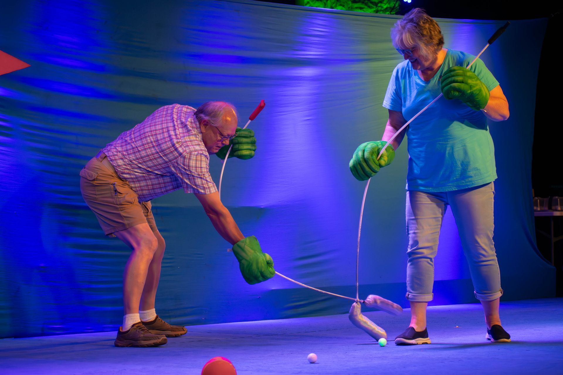 A man and a woman are playing a game of golf on a stage.