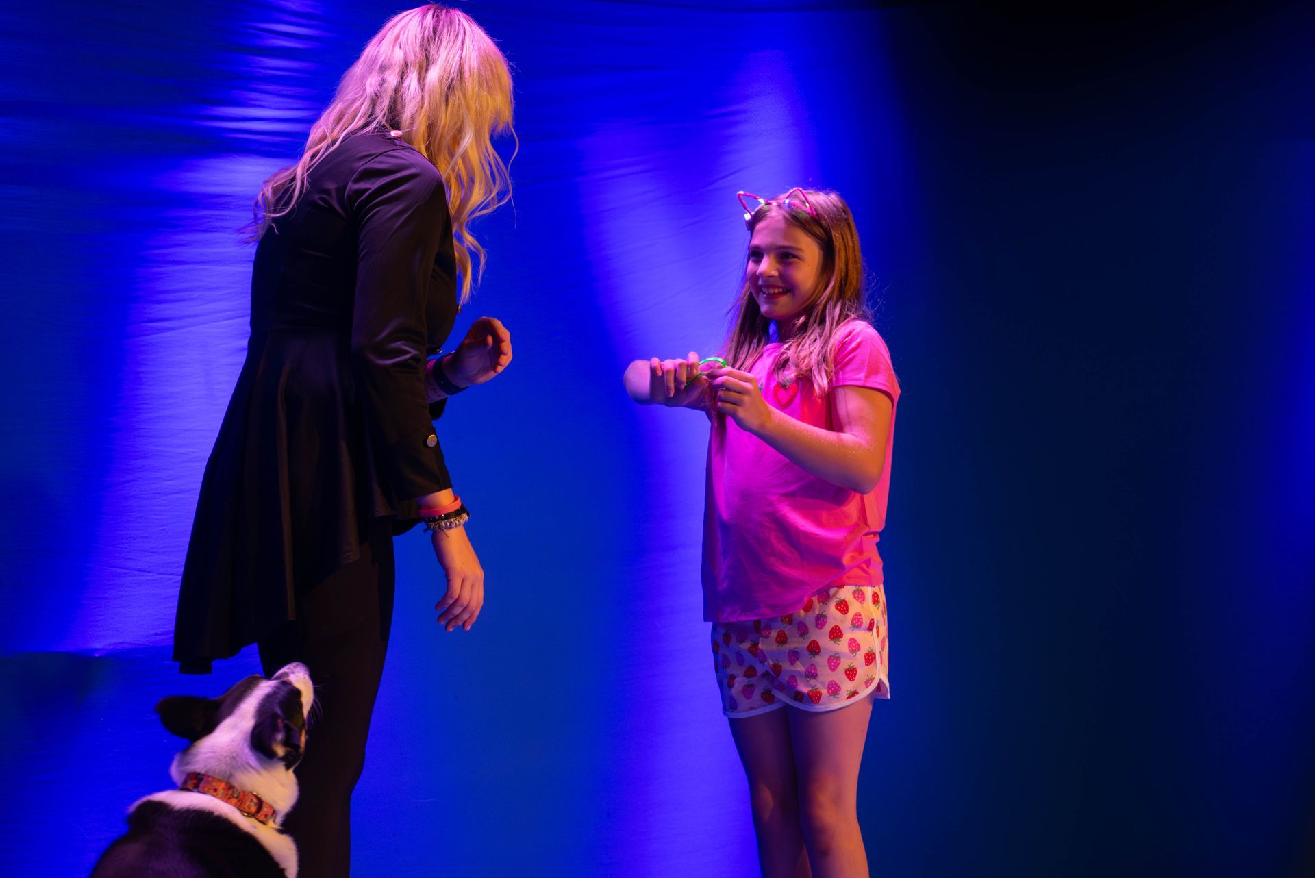 A woman and a girl are standing on a stage with a dog.