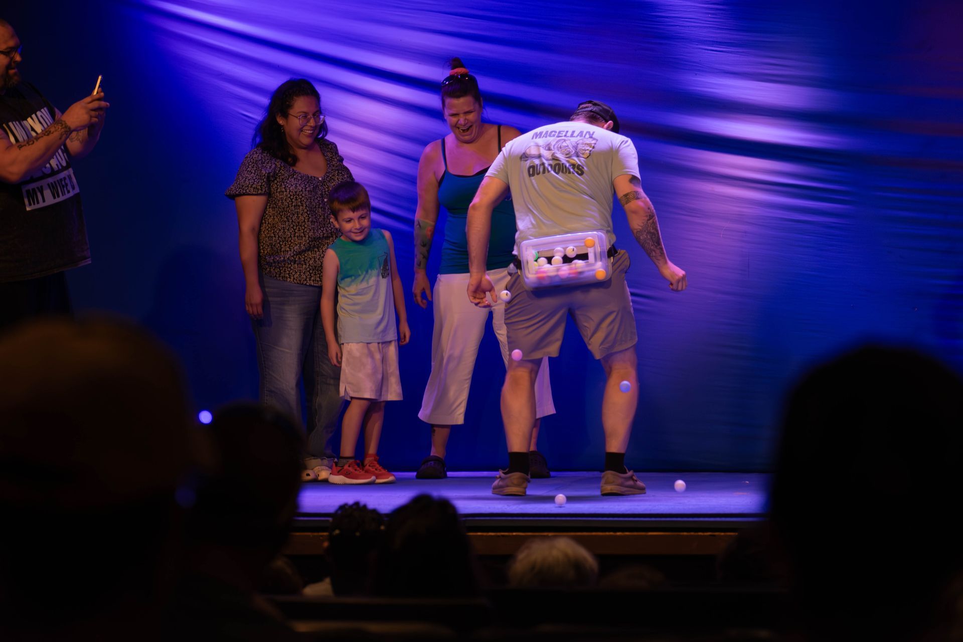 A group of people are standing on a stage in front of a blue curtain.