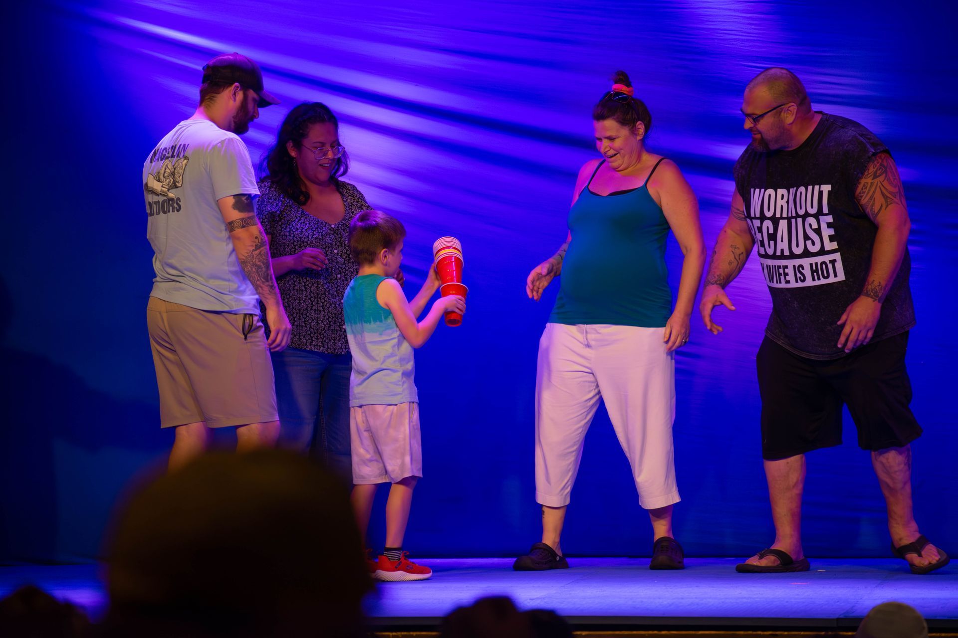 A group of people are standing on a stage holding a stuffed animal.