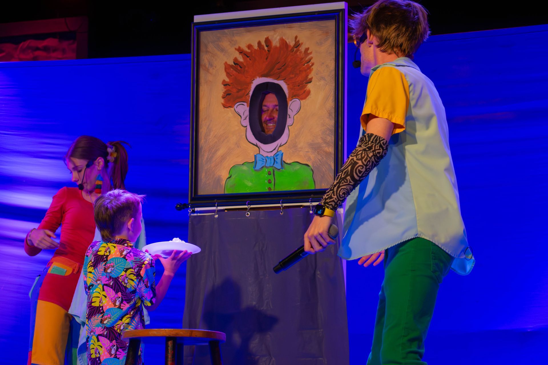A group of children are standing in front of a painting of a clown.