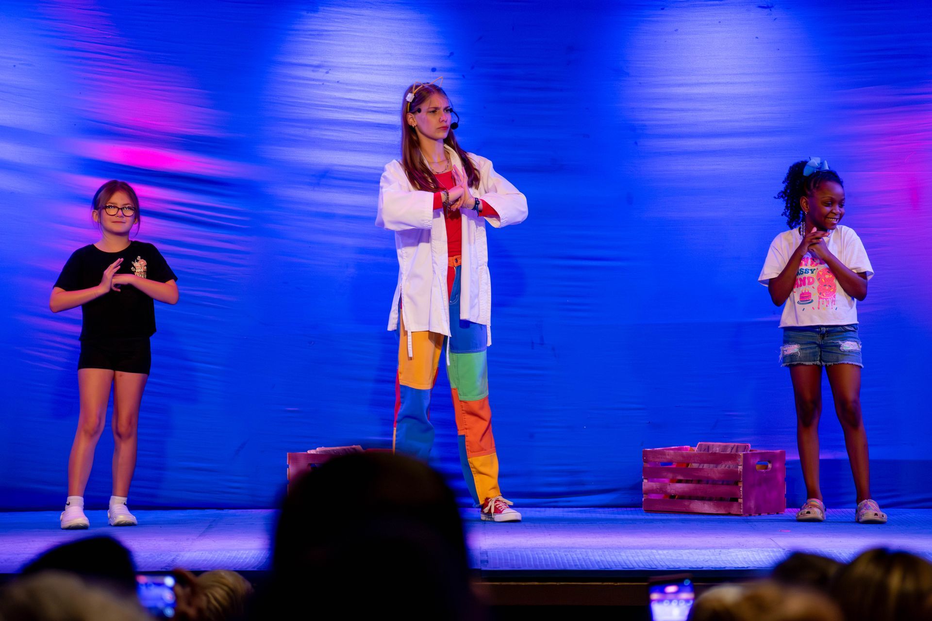 A group of young girls are standing on a stage singing into microphones.
