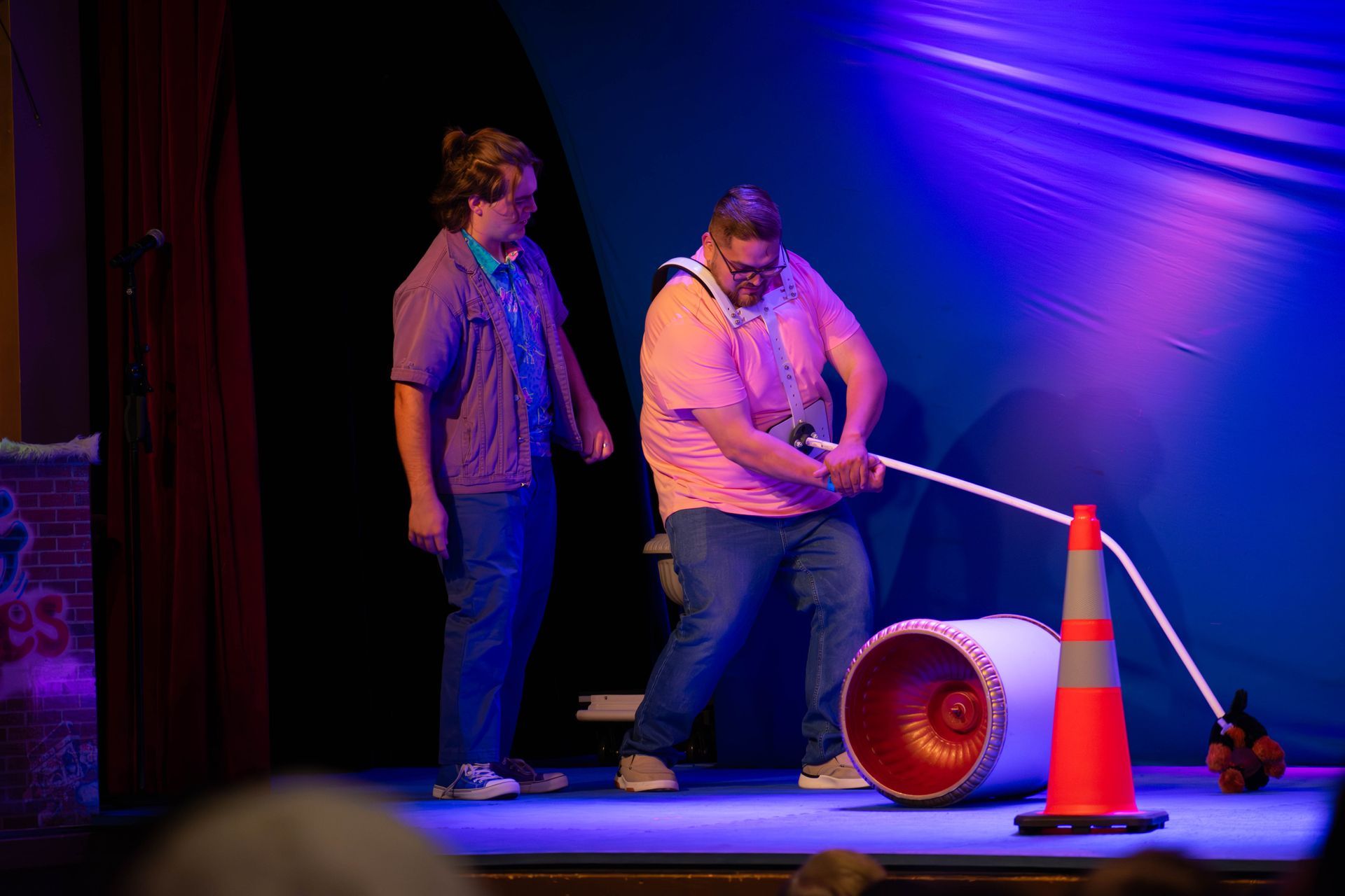 A man and a woman are standing on a stage with a cone and a pipe.