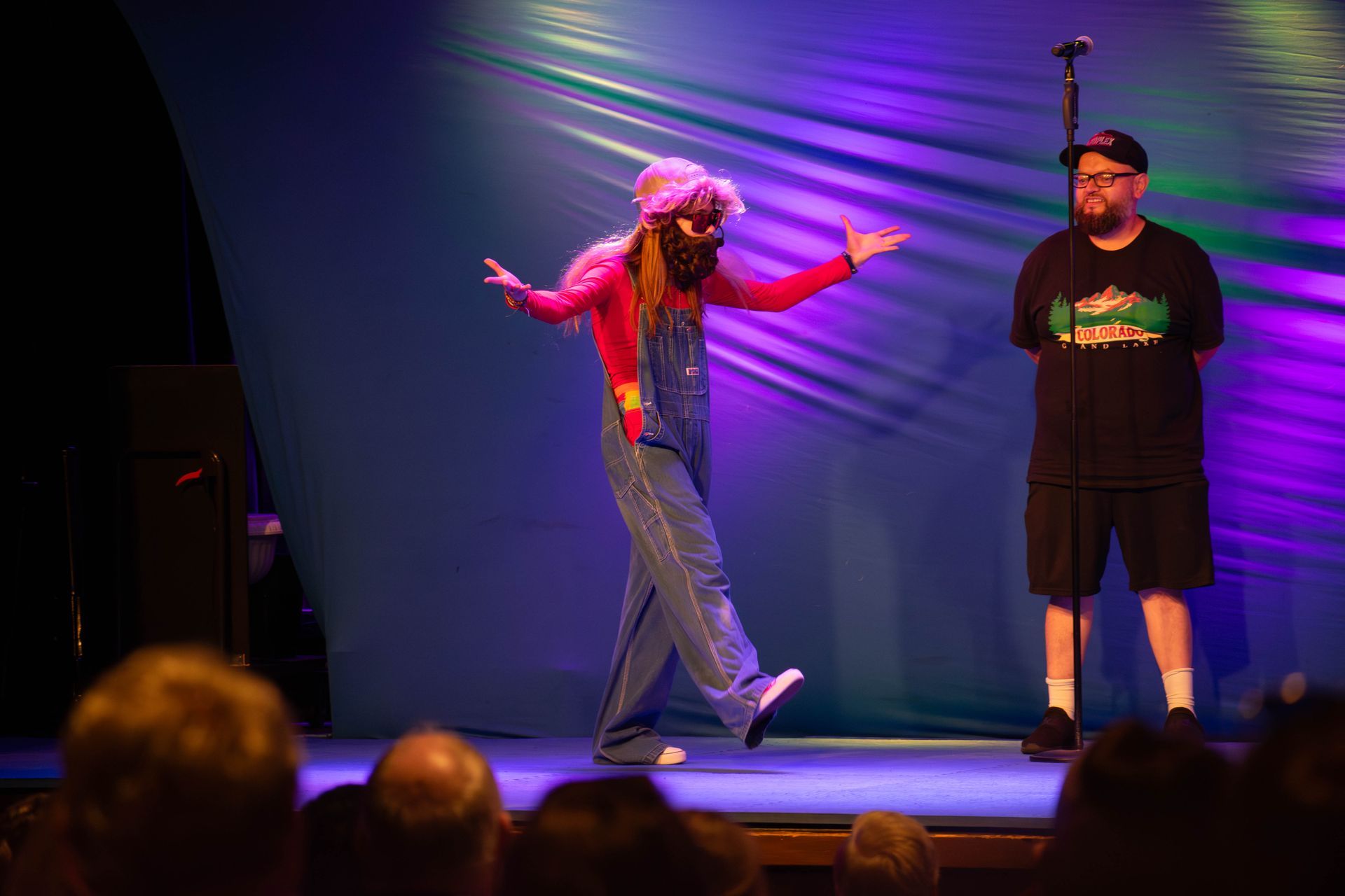 A man and a woman are standing on a stage in front of a microphone.