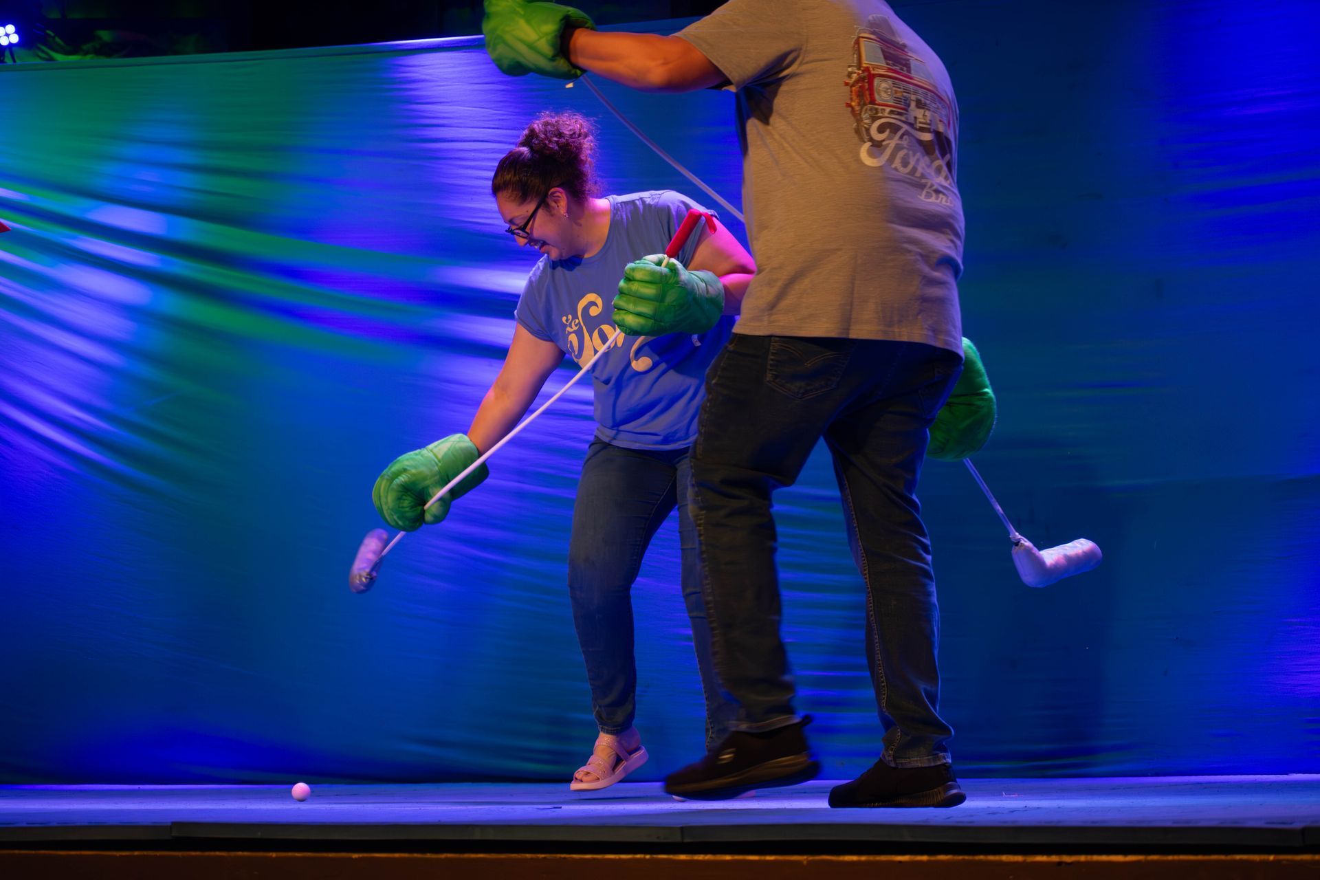A man and a woman are playing with a stuffed animal on a stage.