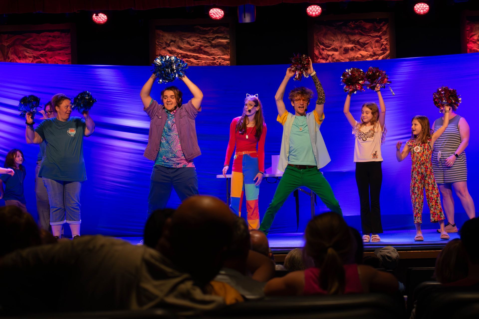 A group of people are standing on a stage holding pom poms.