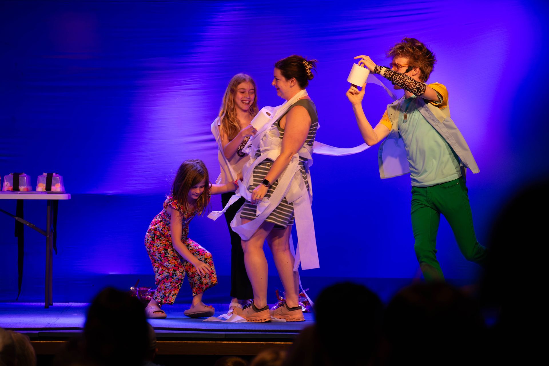 A group of children are playing with toilet paper on a stage.