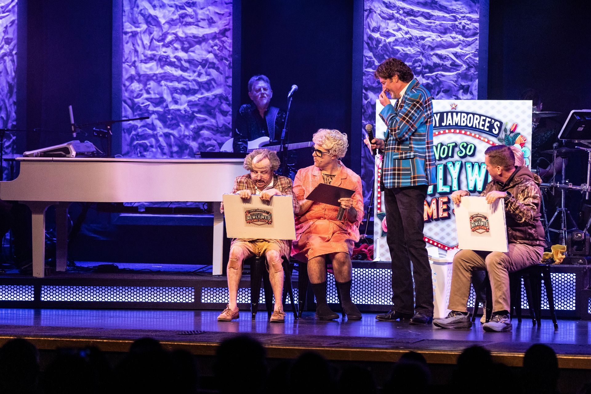 A group of people are standing on a stage in front of a piano.