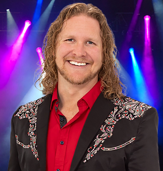 A man with long hair is wearing a red shirt and a black jacket