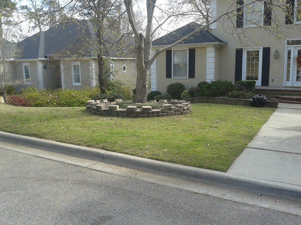A house with a circular brick border around a tree in the front yard.