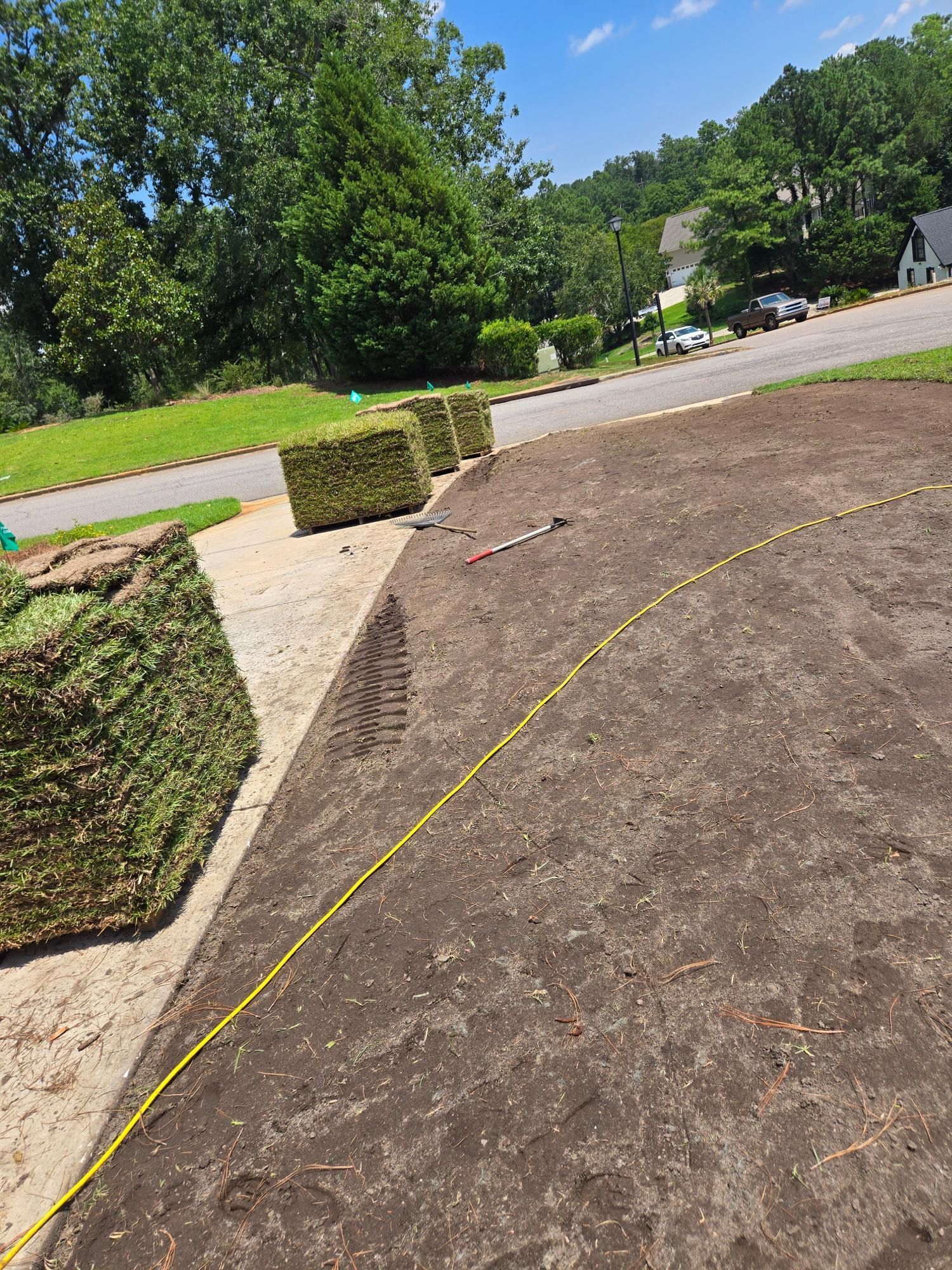 Yard with cut sod and a prepared area for installation, a power cord extends across the ground.