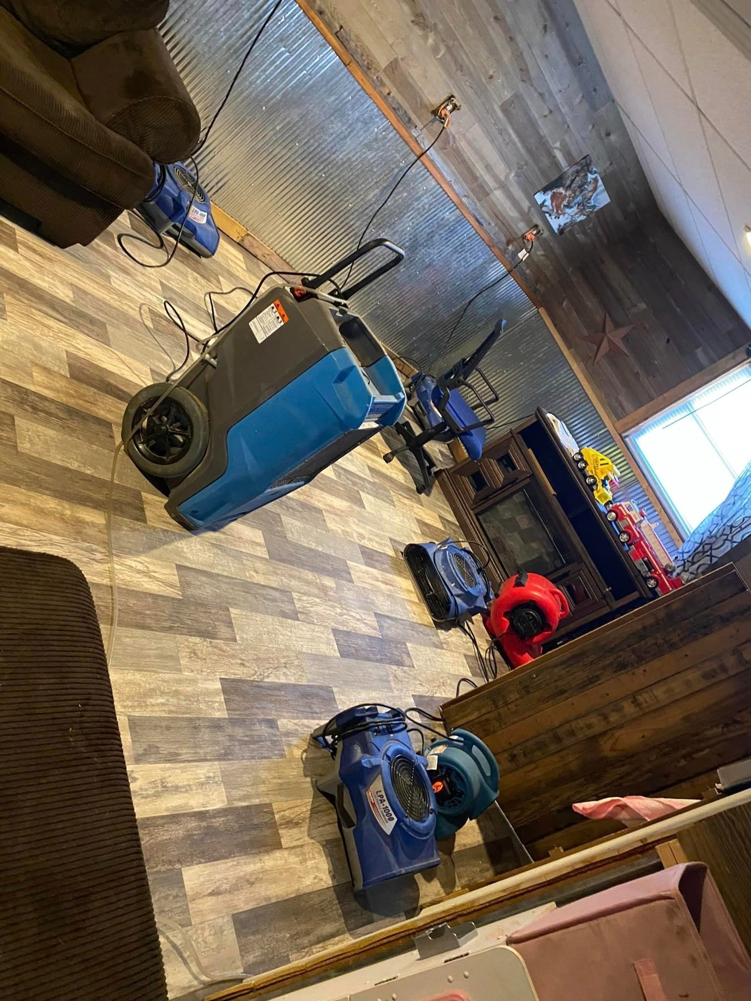 Room with blue and black fans and various items on the wall and floor.
