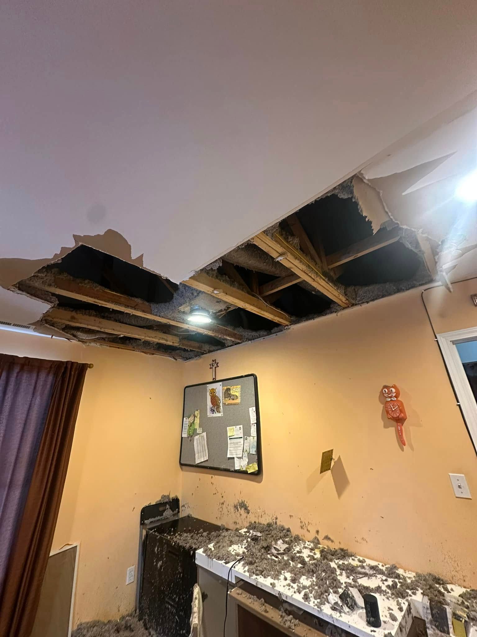 Damaged ceiling with large holes. Debris covers the counter and floor.