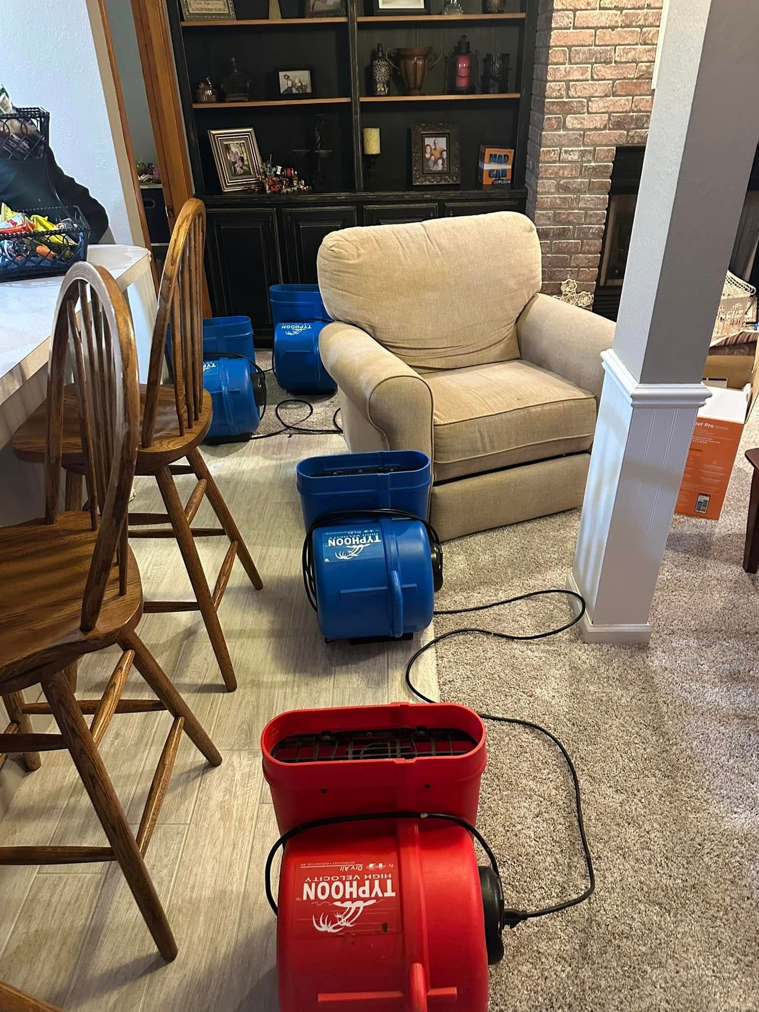 Red and blue air movers set up on carpeted floor, near furniture and shelves.