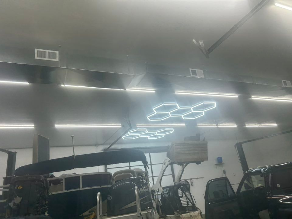 Vehicles in a workshop under bright lights, a modern hexagonal light fixture is visible.