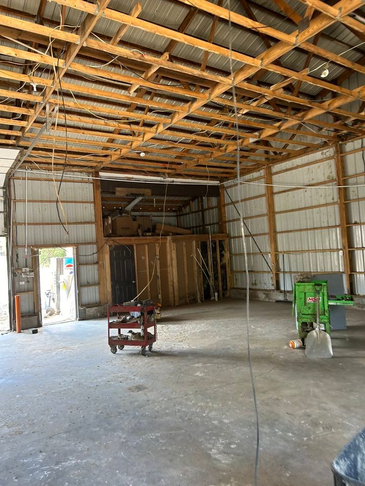 Interior of a large, empty barn with a wooden frame and metal siding. A small loft is visible.