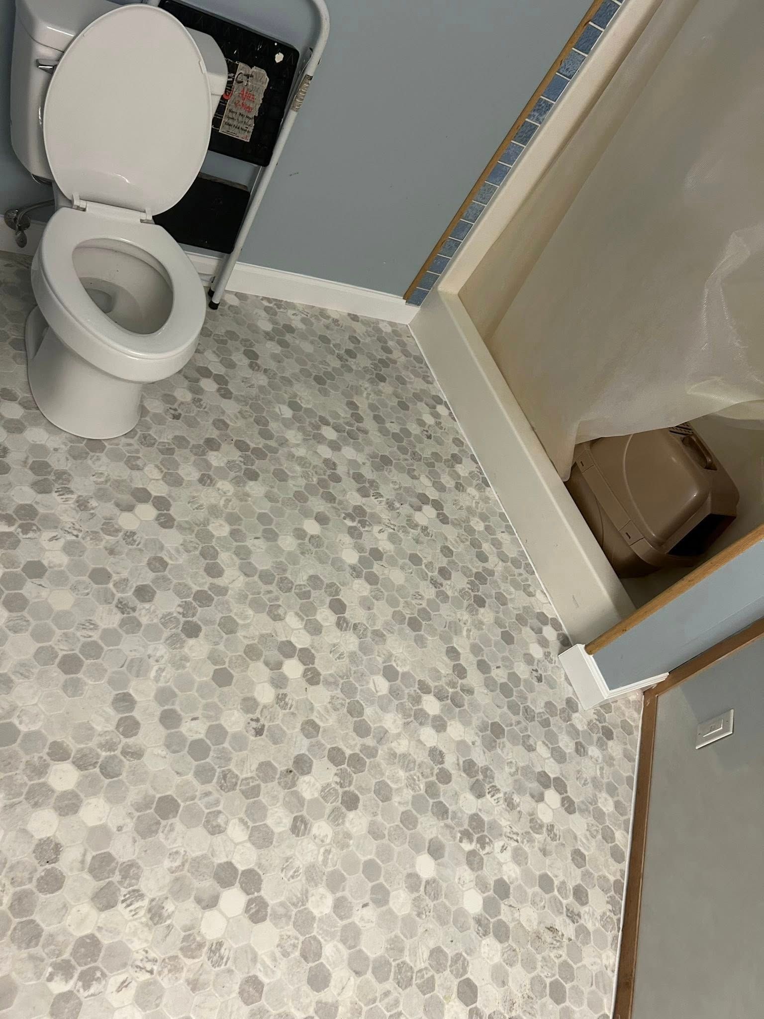 Bathroom with white toilet, grey hexagon floor tiles, and blue walls.