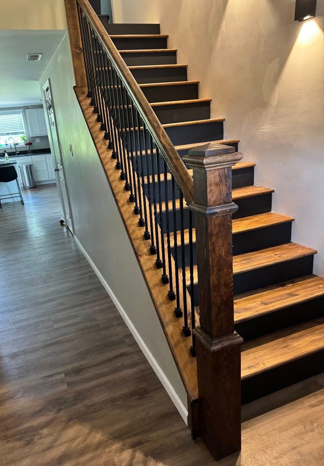 Wooden staircase with black accents and decorative iron railings.
