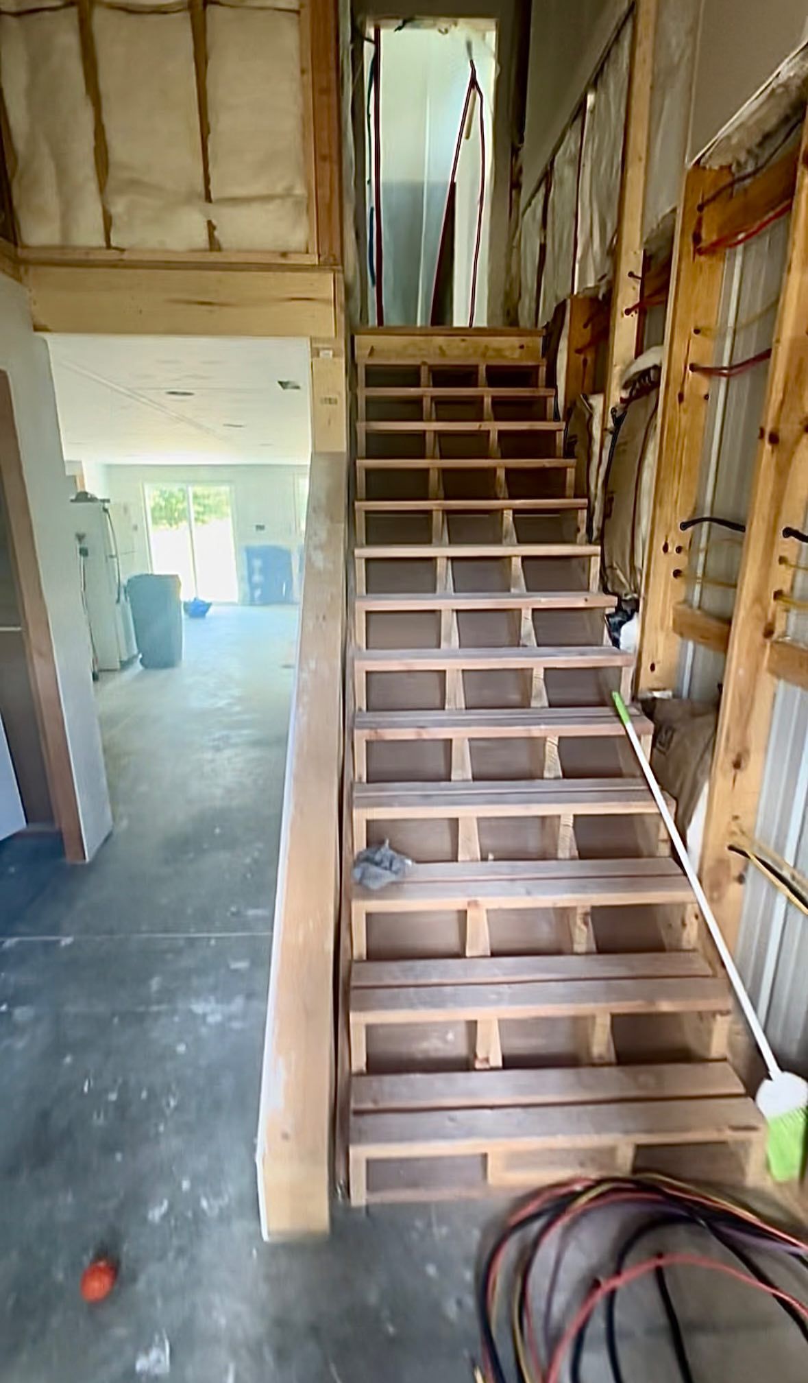 Wooden staircase leading to an upstairs area in a building under construction.