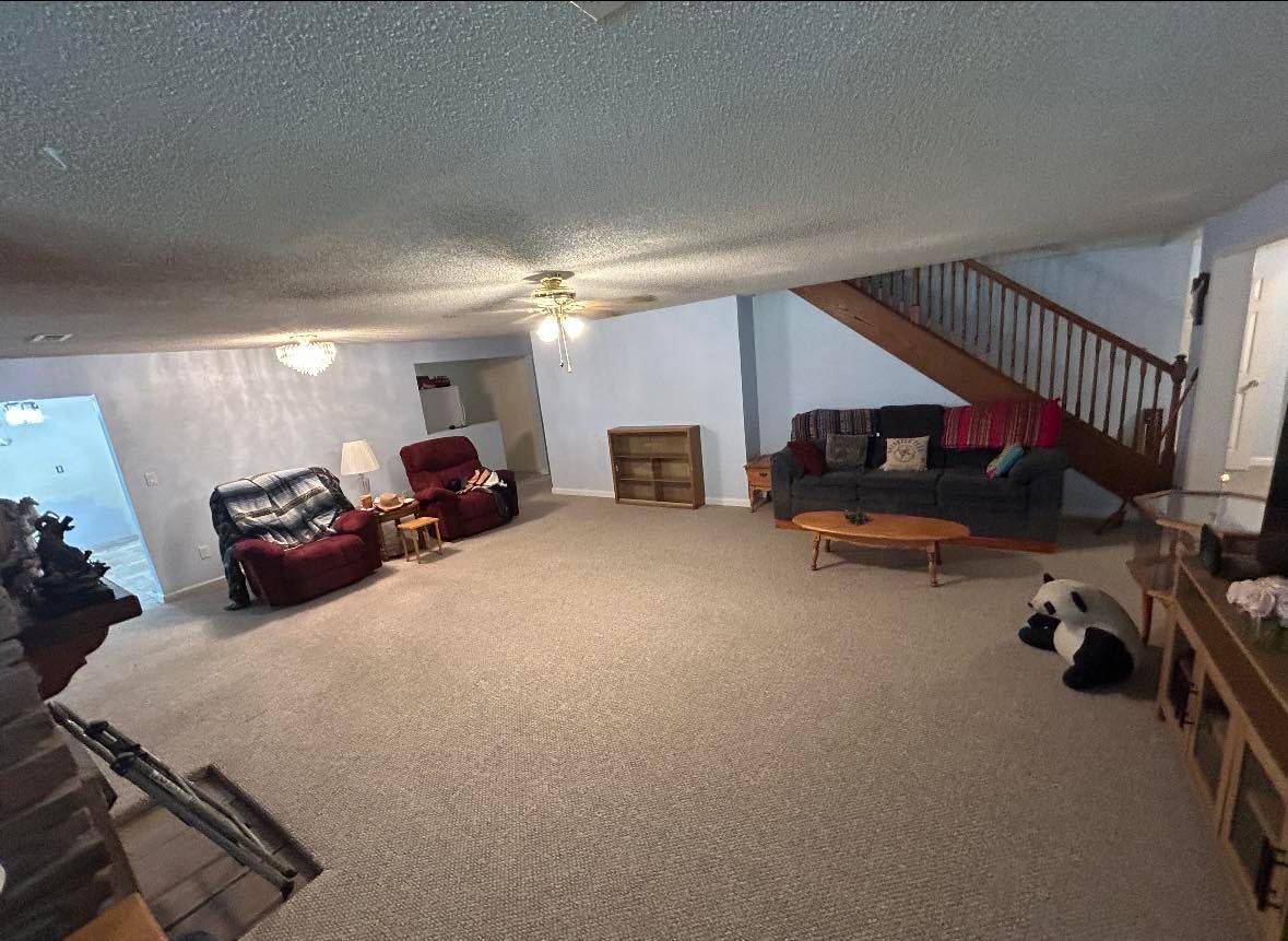 Spacious living room with carpet, stairs, and furniture; includes a panda bear statue.