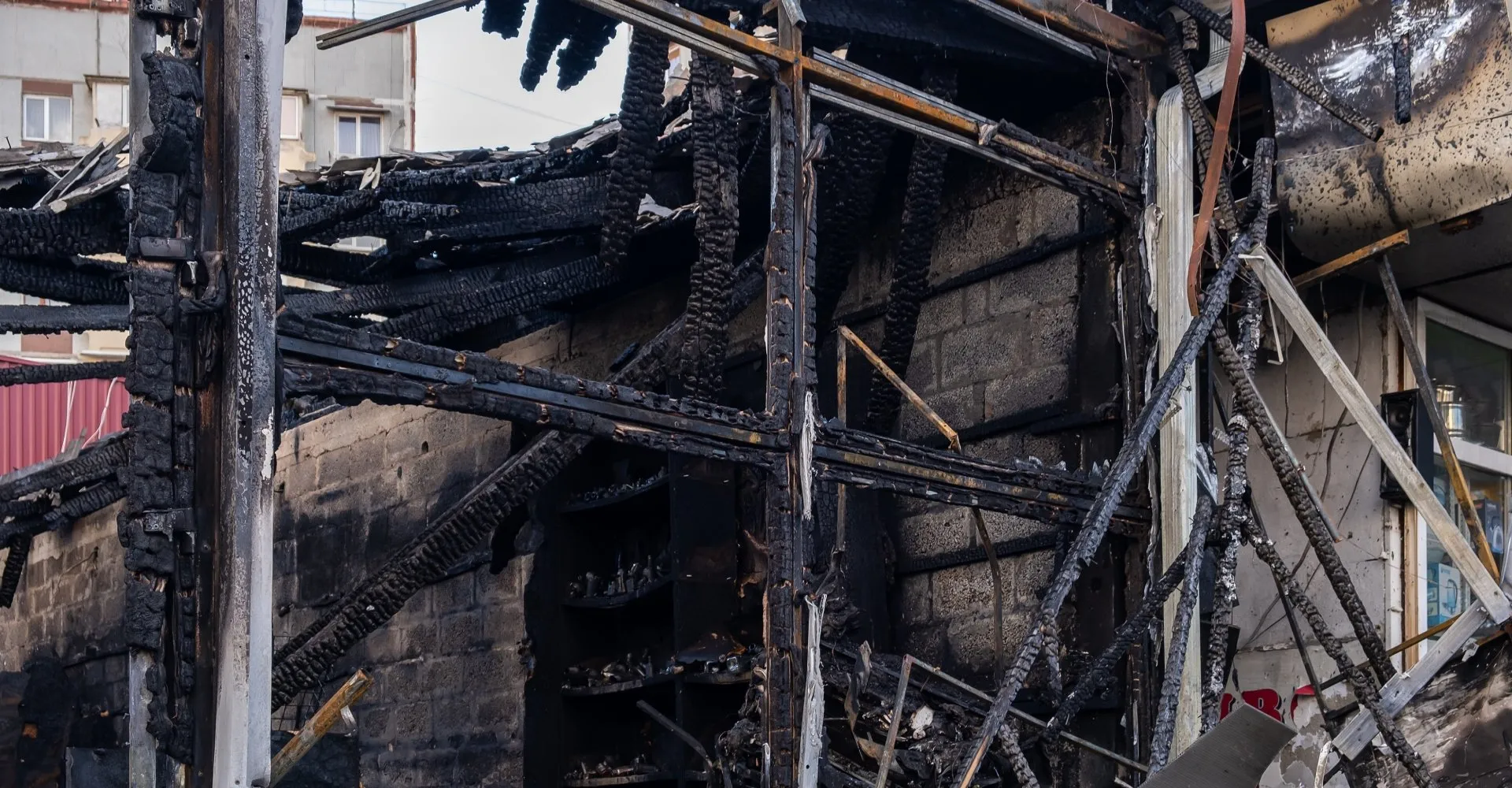 Charred remains of a building after a fire, black wood, exposed beams, and destroyed facade.