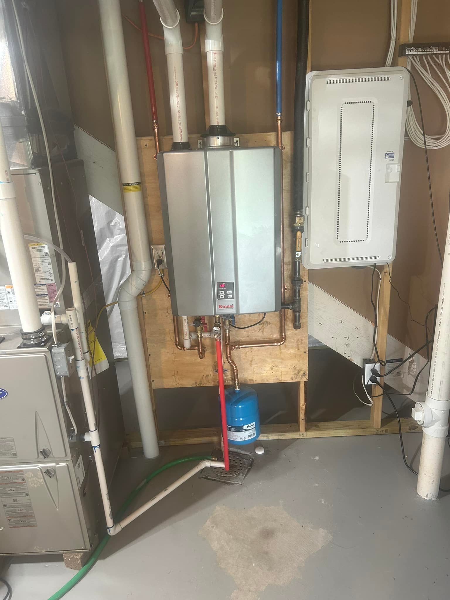 A water heater is installed in a basement next to a furnace.