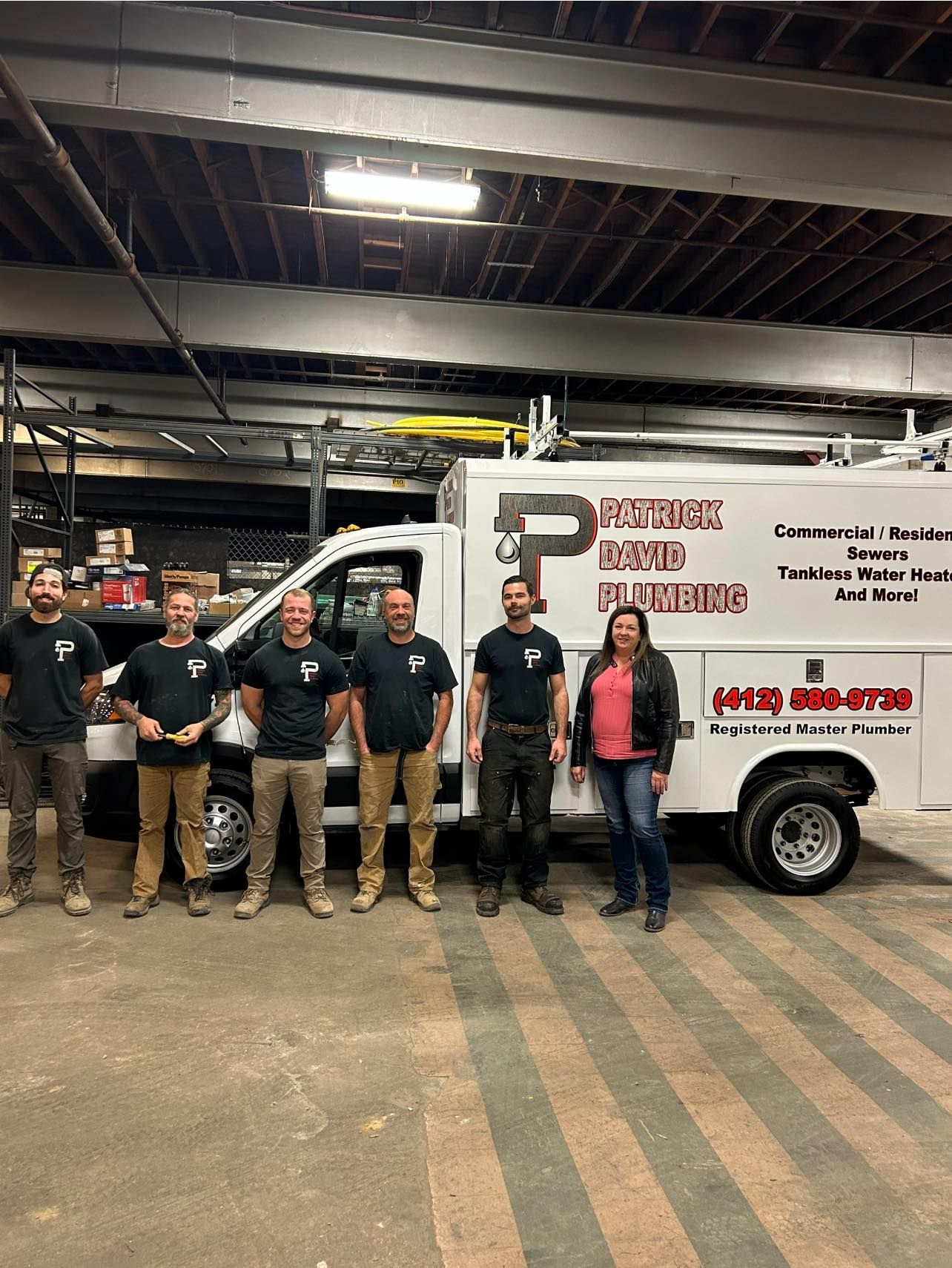 A group of people standing in front of a plumbing truck.