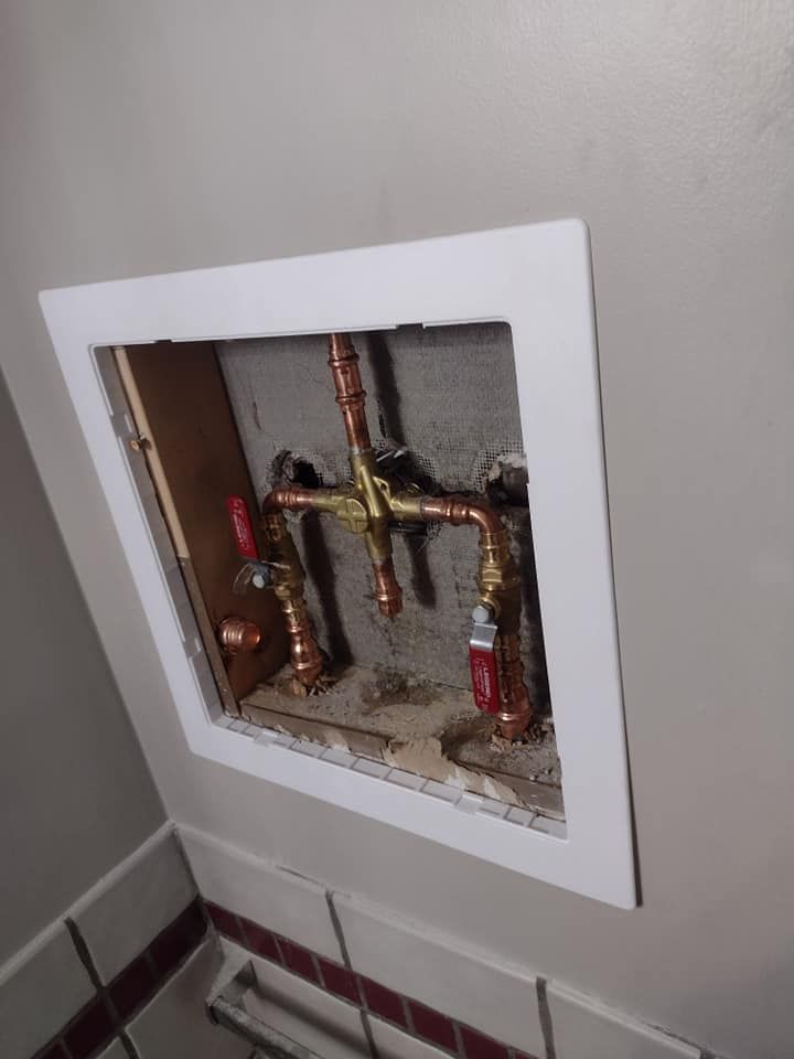 A hole in the wall with copper pipes coming out of it.