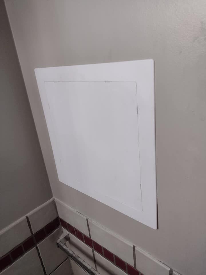 A white door is hanging on a wall in a bathroom.