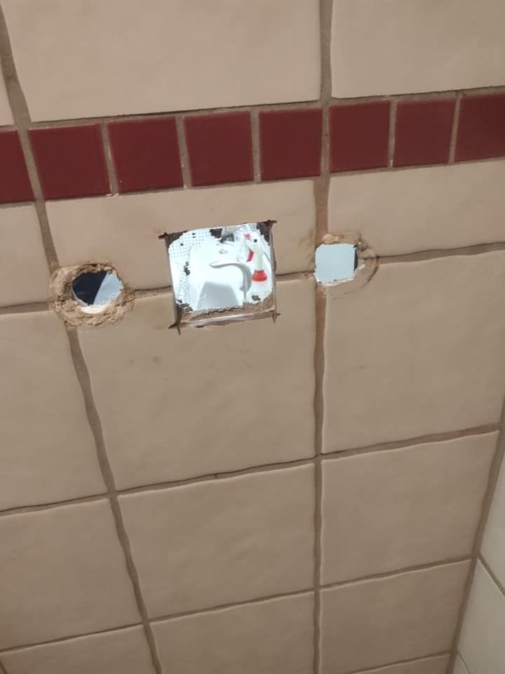 A close up of a tiled wall with holes in it.