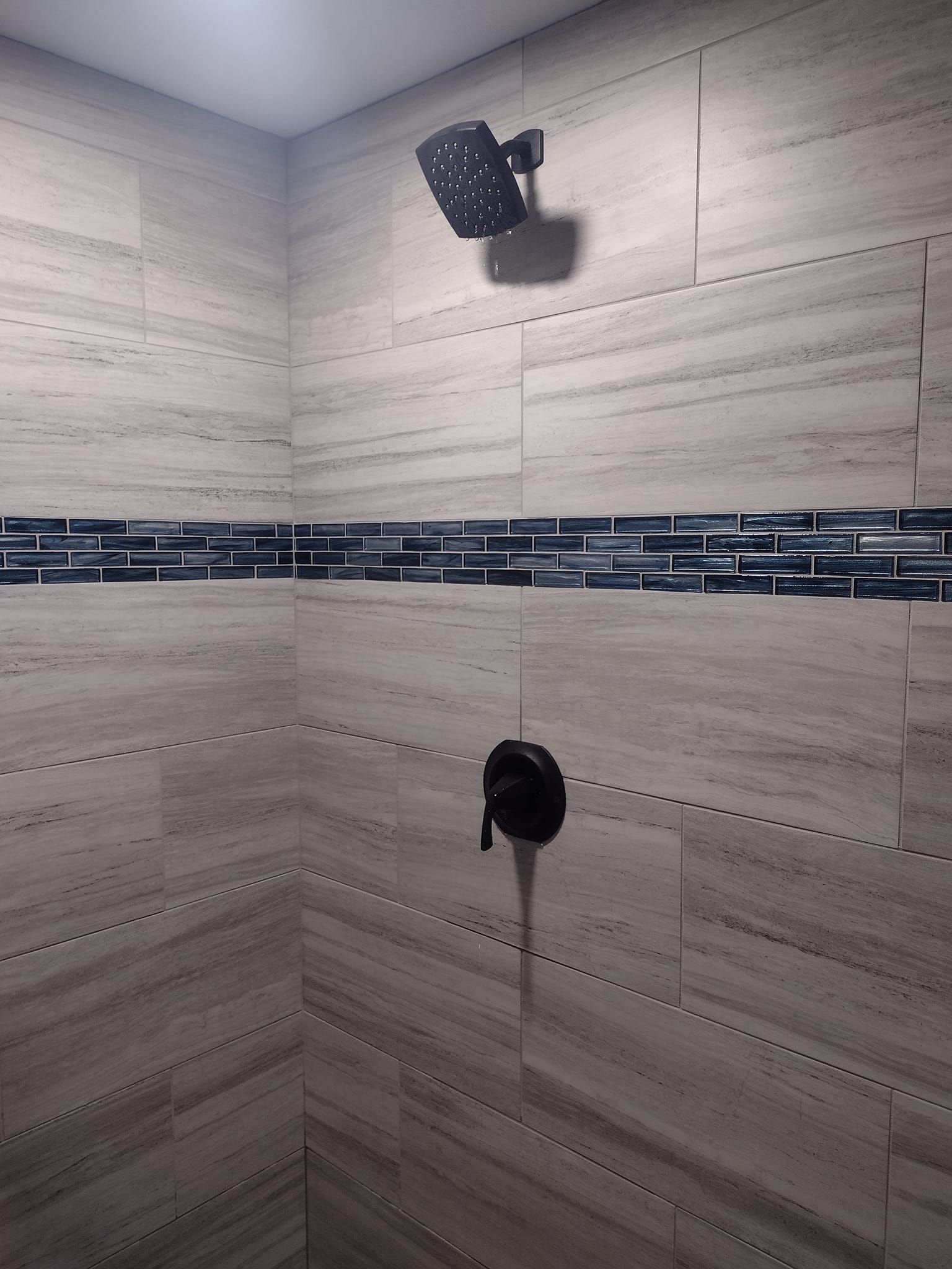 A shower head is hanging from the ceiling in a bathroom.