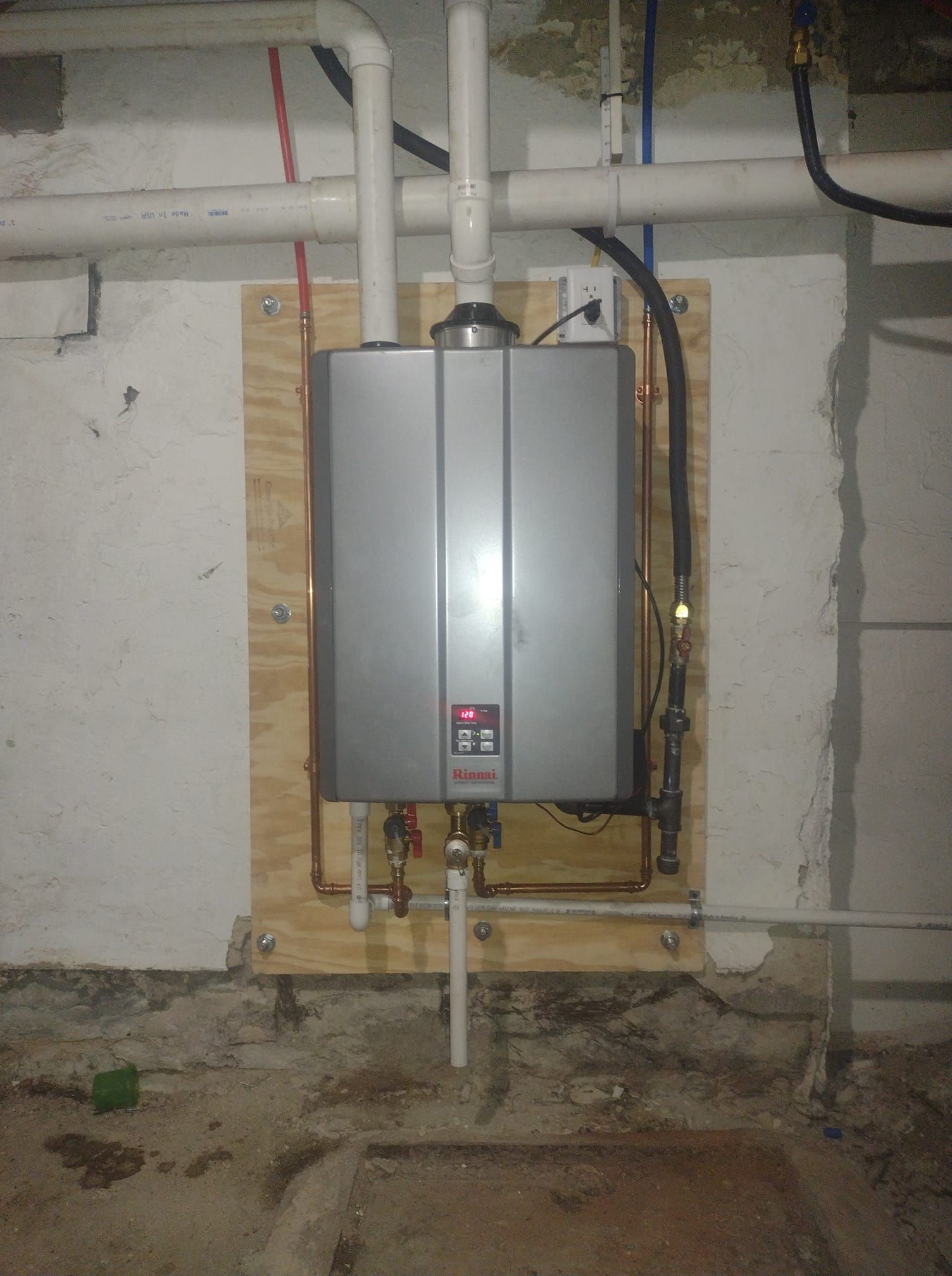 A water heater is mounted to a wall in a basement.