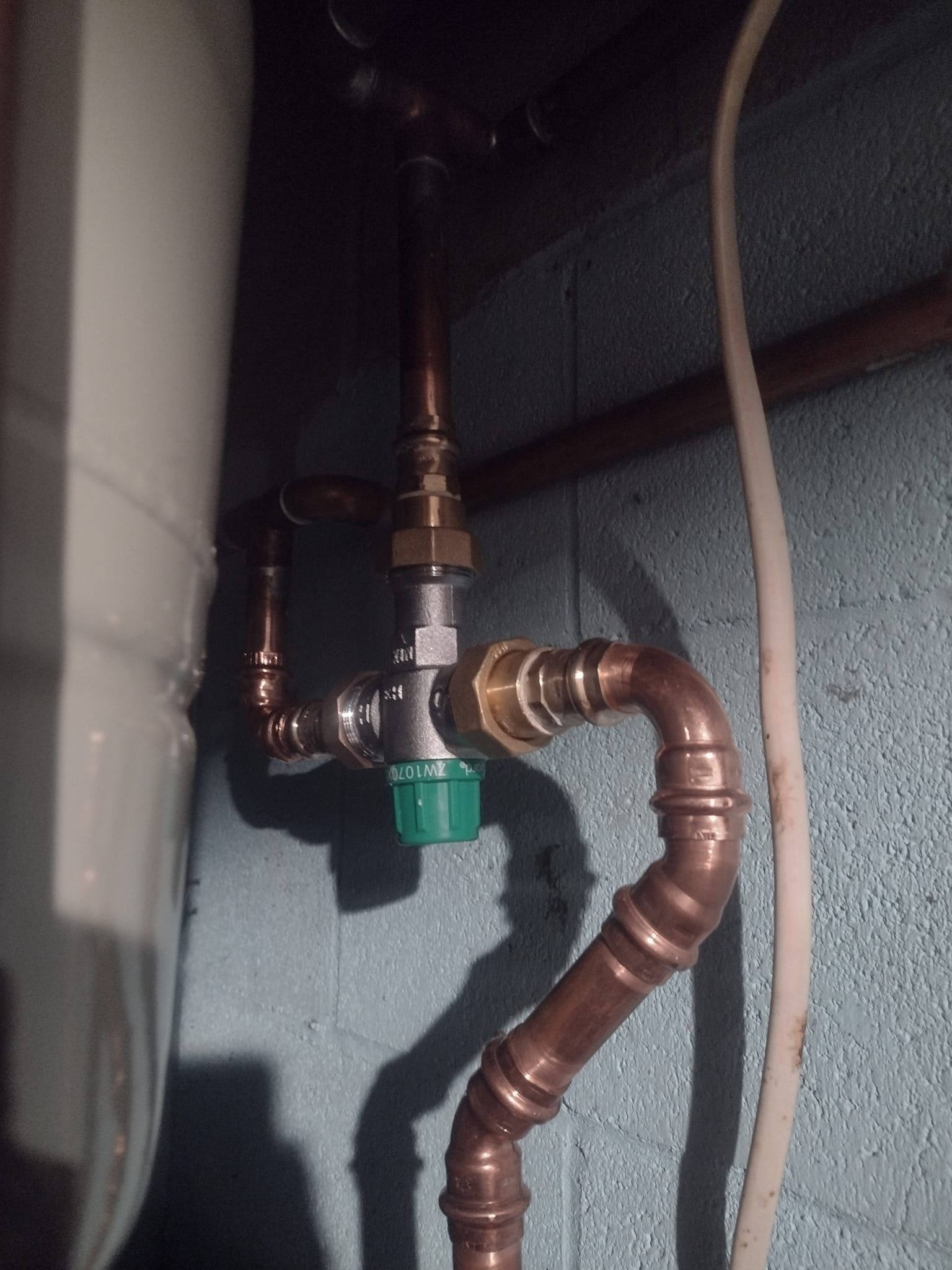 A copper pipe with a green valve attached to it