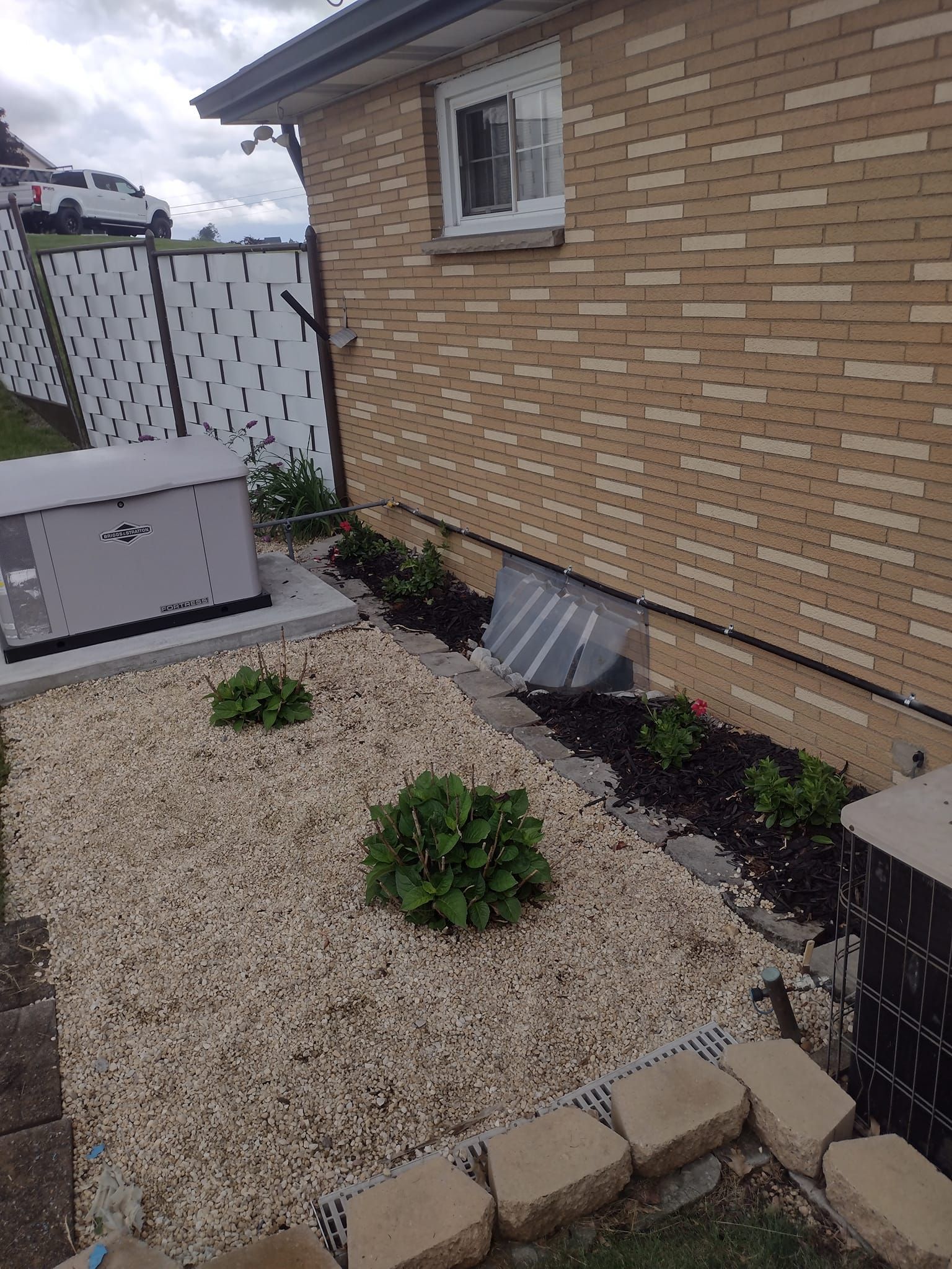 A brick house with a generator in the backyard.
