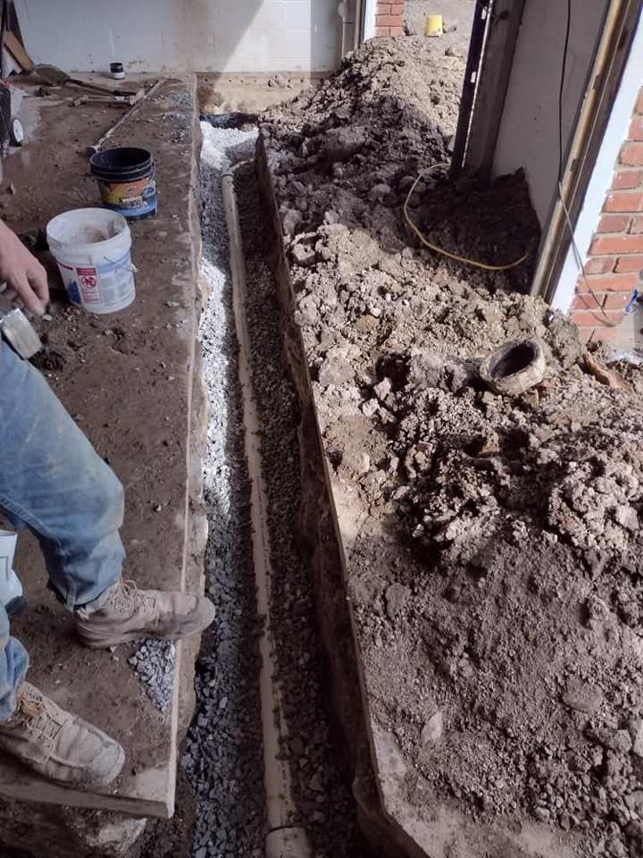 A person is digging in the dirt next to a brick wall.