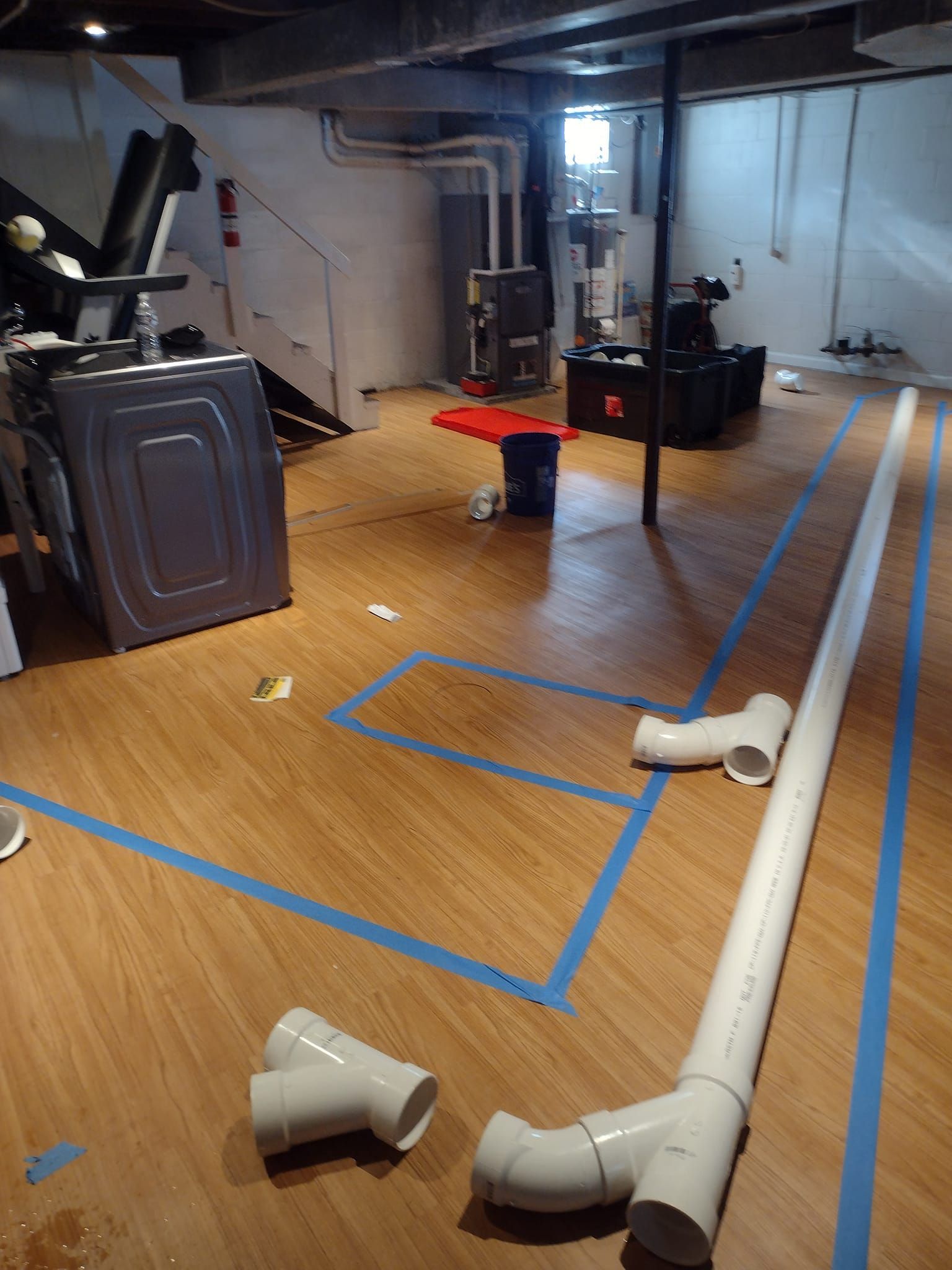 A basement with a washer and dryer and pipes on the floor.