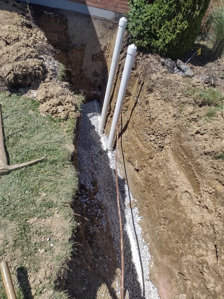 A drain pipe is being installed in a hole in the ground.