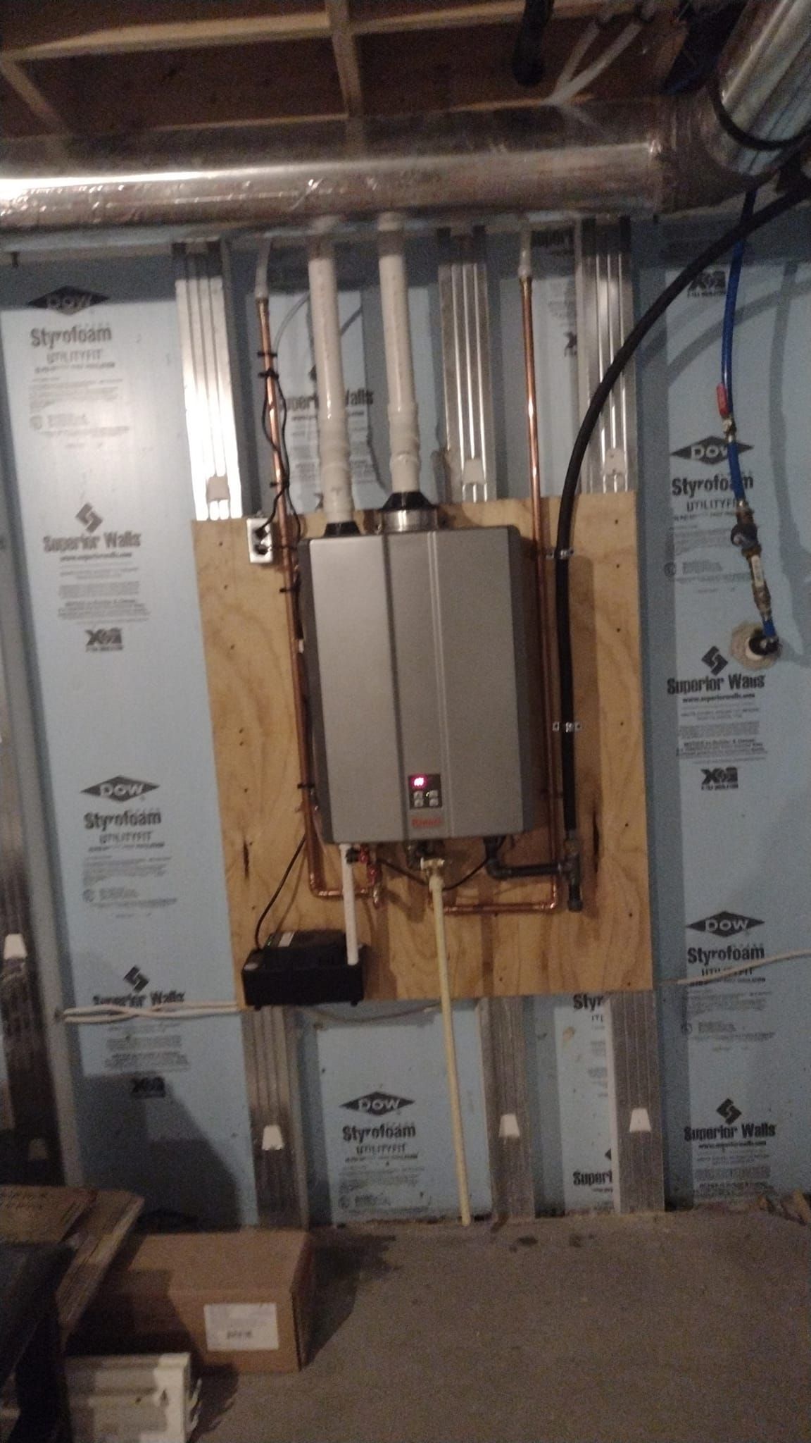 A water heater is mounted to a wall in a basement.