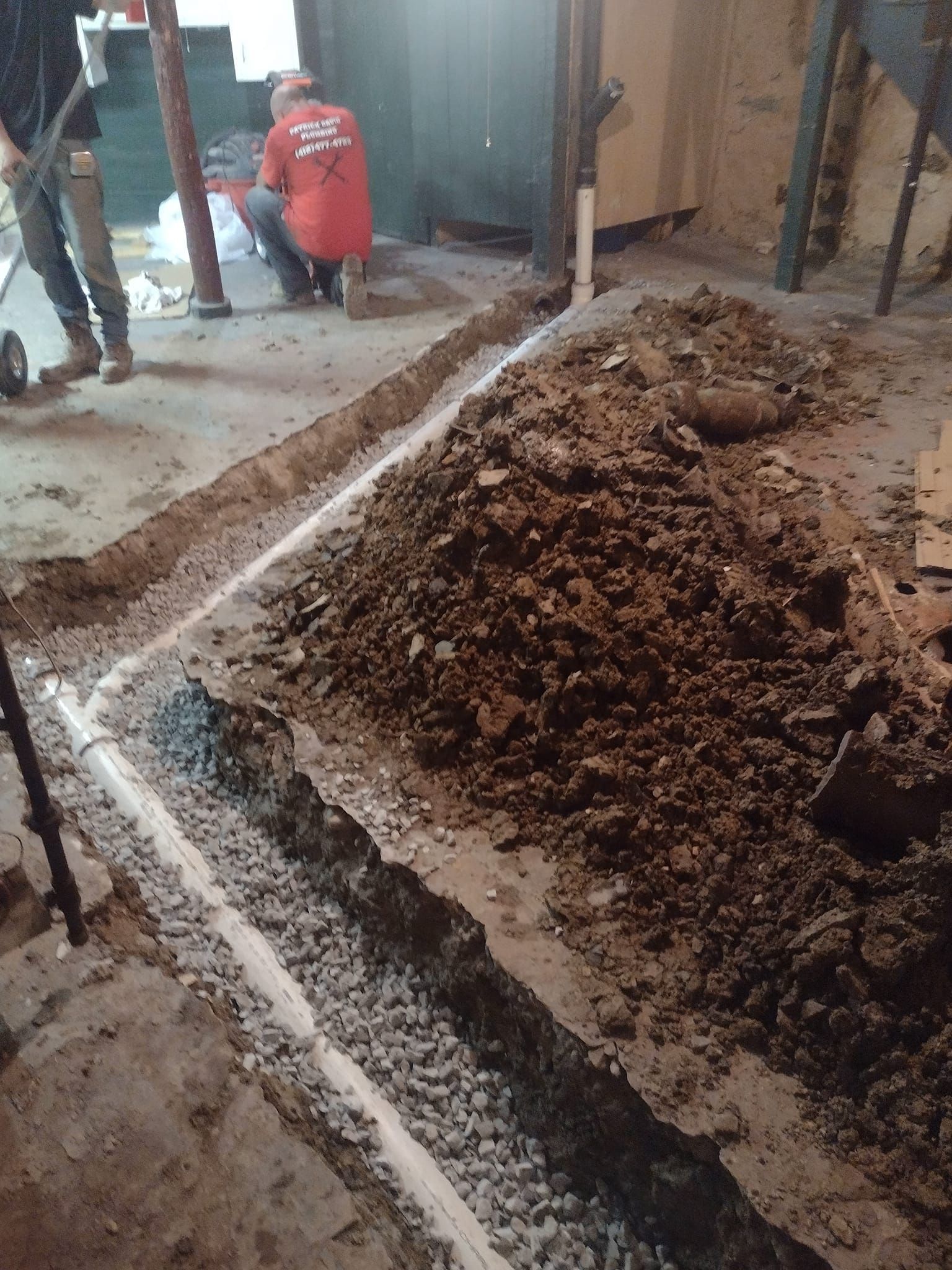 A man is kneeling on the floor next to a pile of dirt.