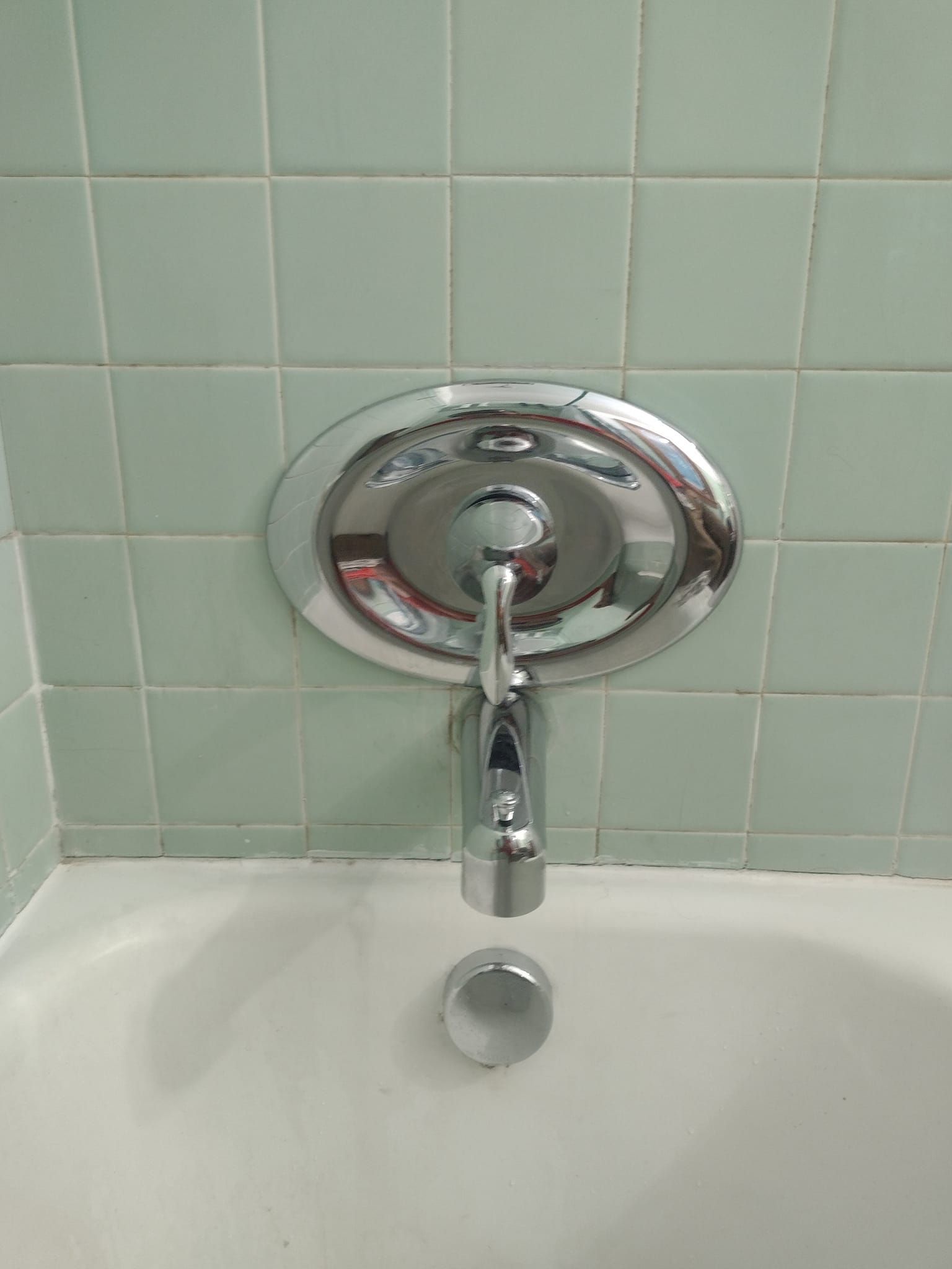 A bathtub with a chrome shower head attached to the wall.
