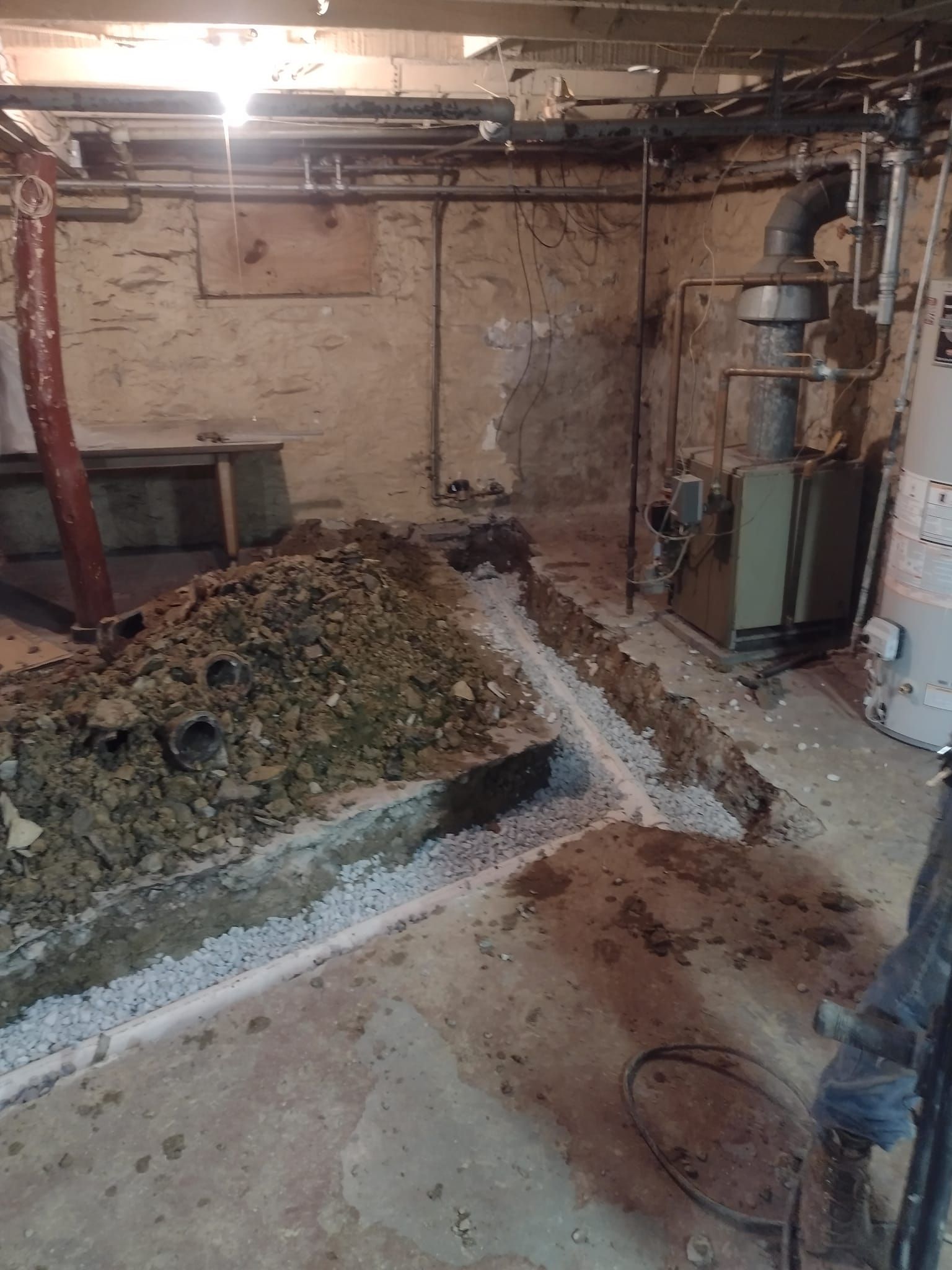 A dirty basement with a lot of dirt and pipes.