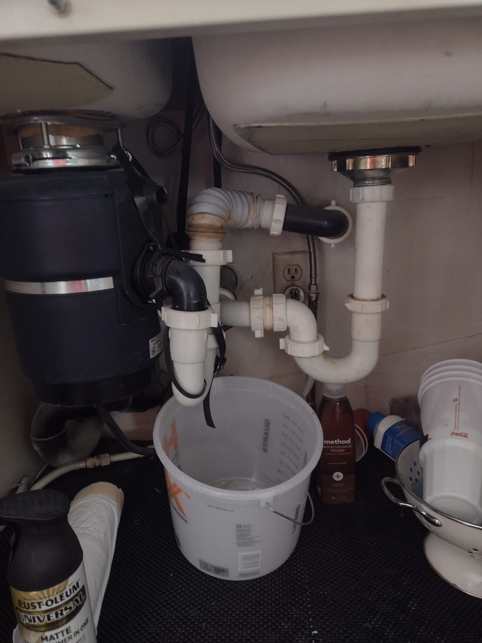 A sink with a garbage disposal and a bucket underneath it.