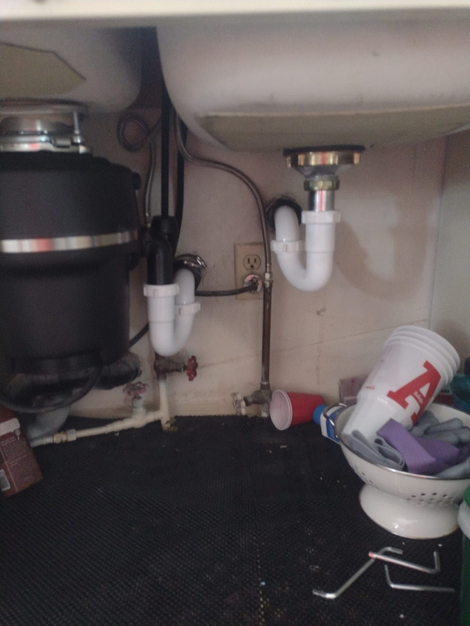 A cup with the letter a on it sits under a sink