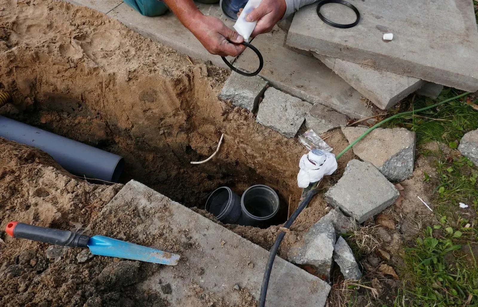 A man is working on a pipe in the dirt.