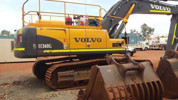 A yellow and black volvo excavator is parked in a dirt lot