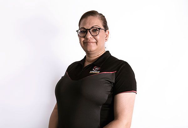 A woman wearing glasses and a black shirt is standing in front of a white background.