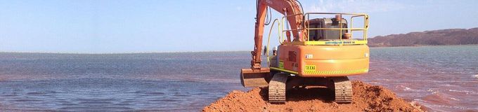 An excavator is digging a hole in the middle of a body of water.