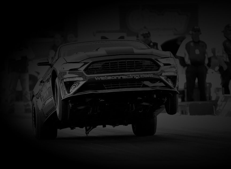 A black and white photo of a ford mustang driving down a road.